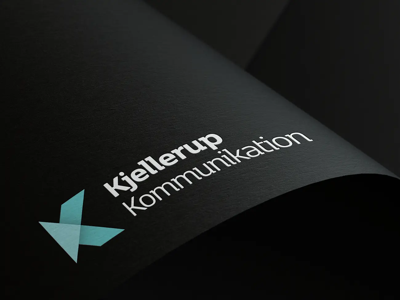 Design af logo til Kjellerup Kommunikation på sort papir