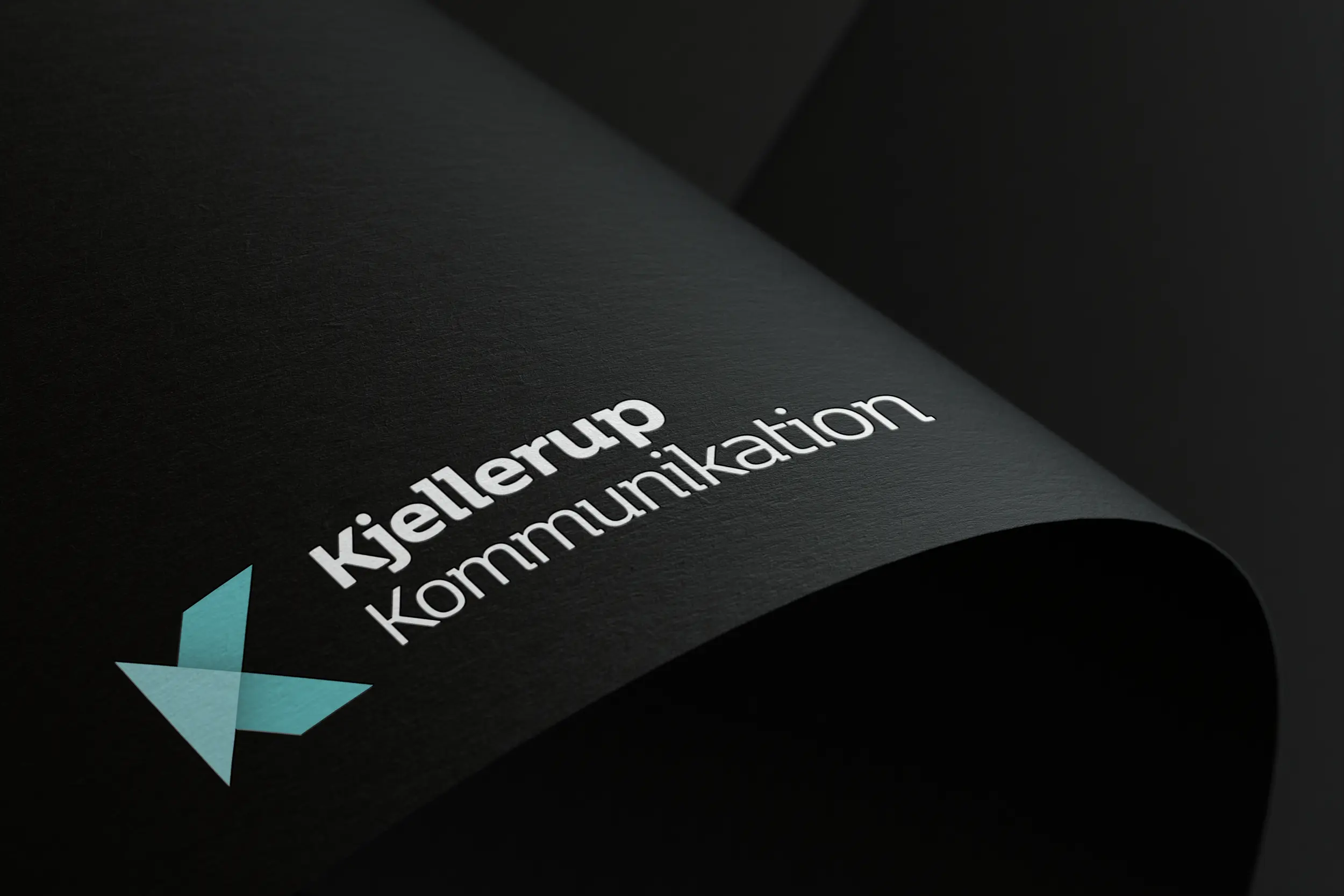 Sort papir med Kjellerup Kommunikation logo i hvid
